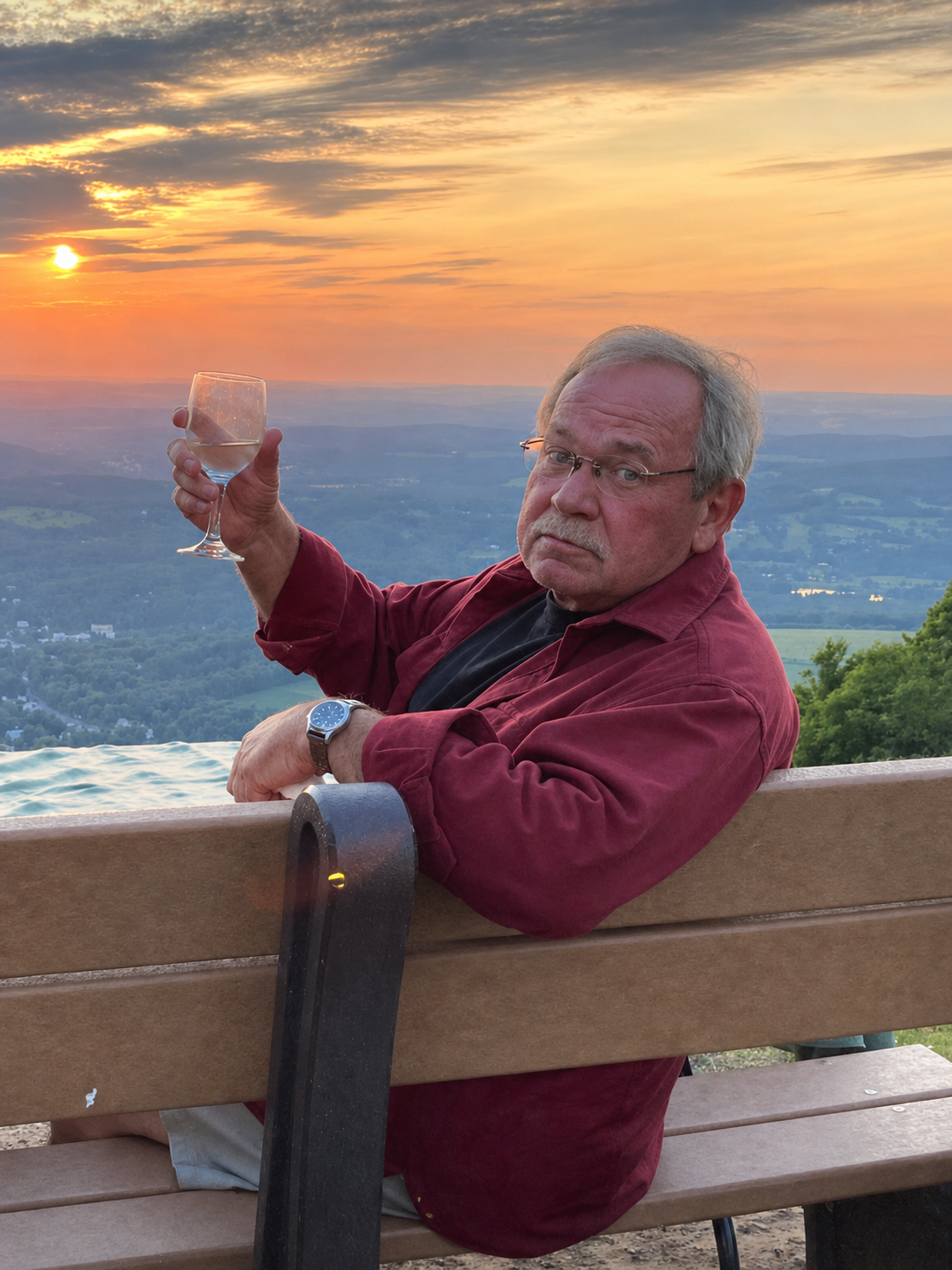Jon Barber raising a glass at sunset with a mountain view behind him
